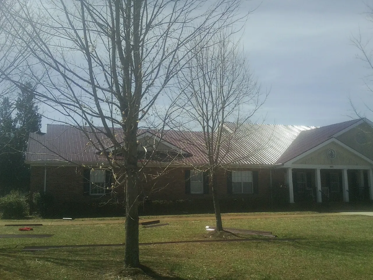 Red metal roof on a brick building seen from the front lawn in Okahumpka