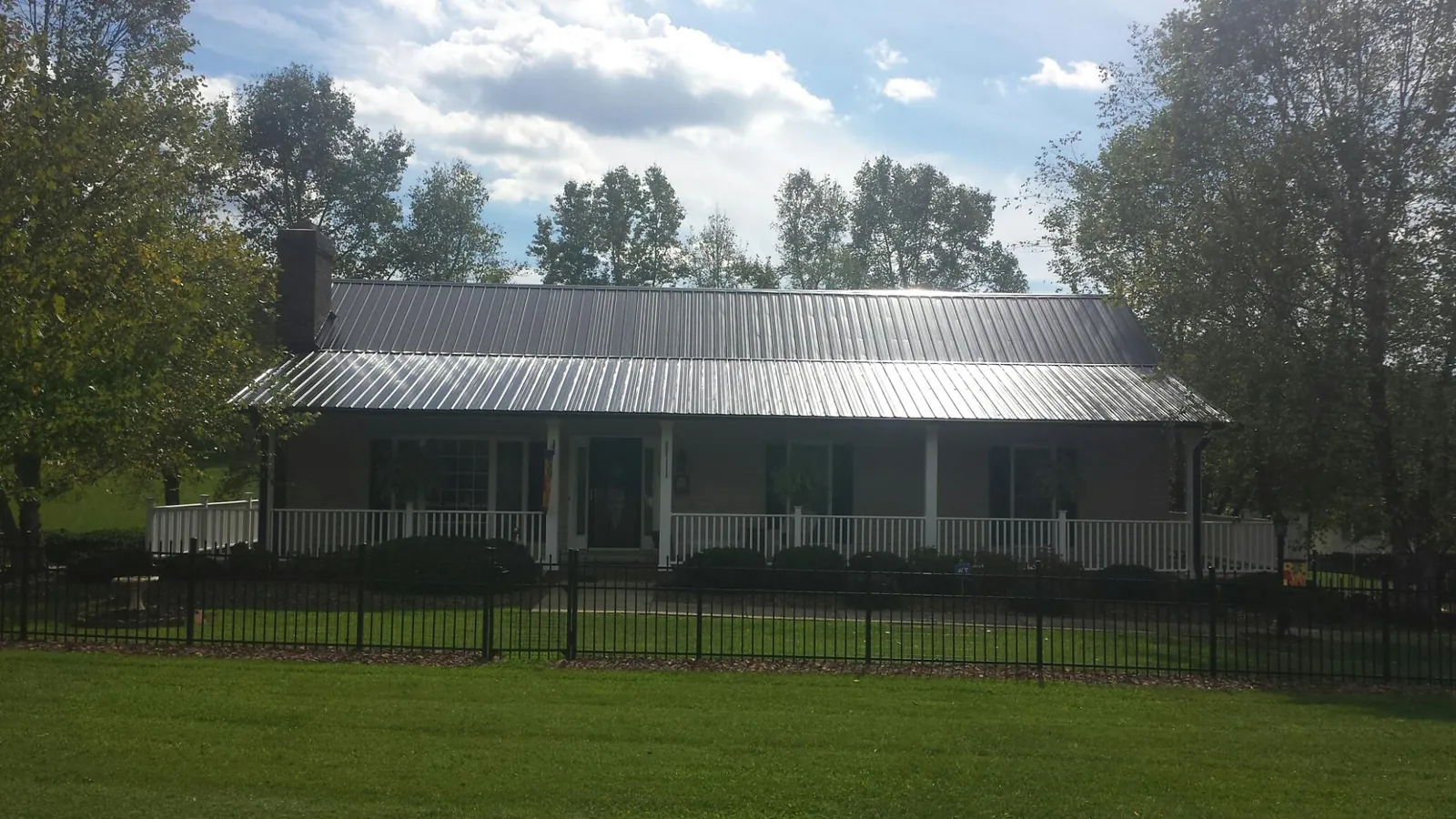 Gray metal roof on a brick ranch with a full width front porch — Gutter Guard Installation work by our crew in Okahumpka