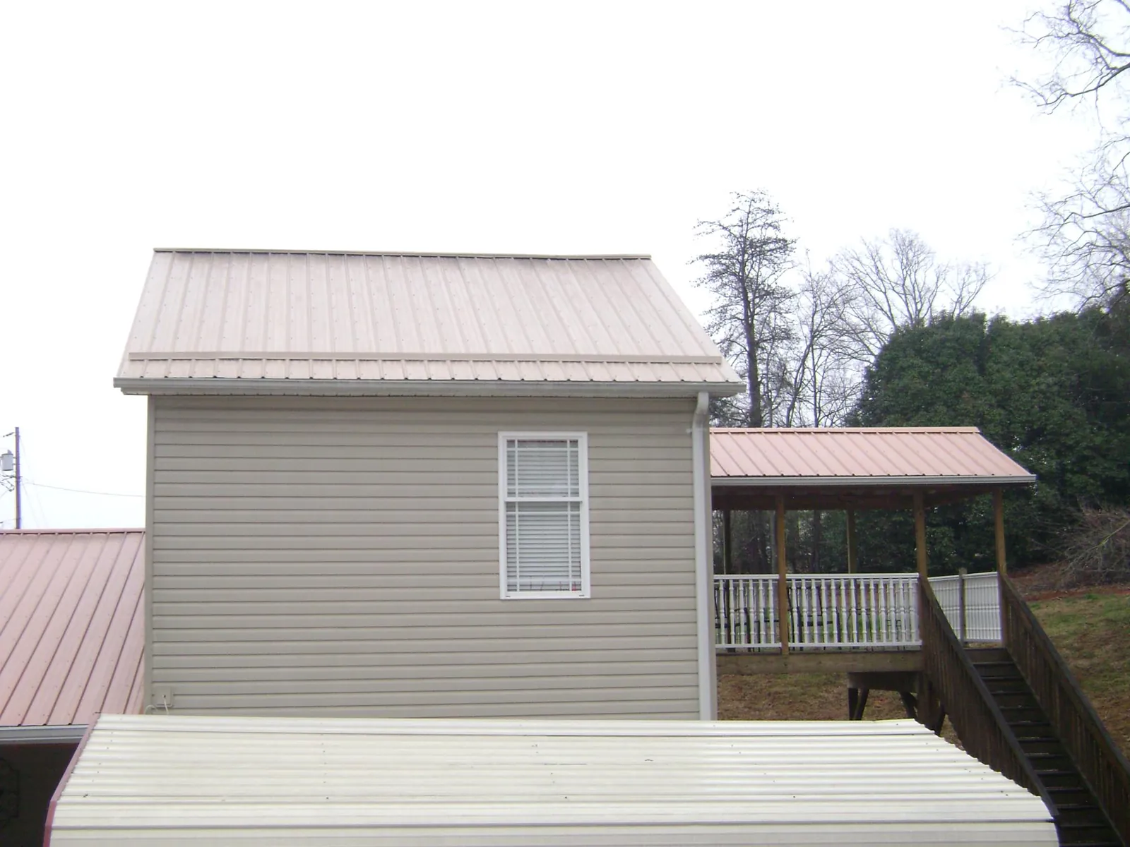 Tan metal roofs on a two story addition and attached porch, from a Roof Replacement job in Okahumpka